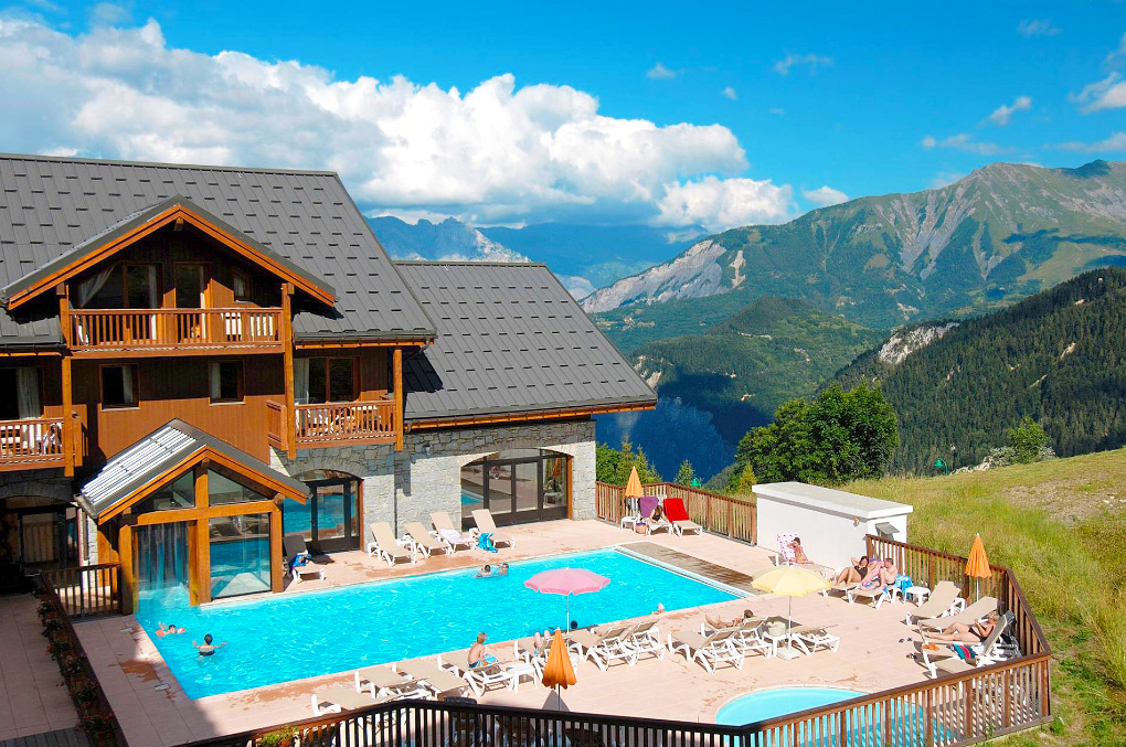 Extérieur et piscine extérieure chauffée de la résidence de vacances Goélia Les Alpages du Corbier en été
