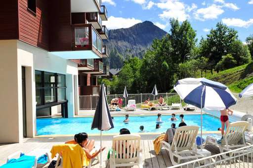 Indoor and outdoor heated swimming pool of the holiday residence Goélia Les Terrasses du Corbier au Corbier in summer
