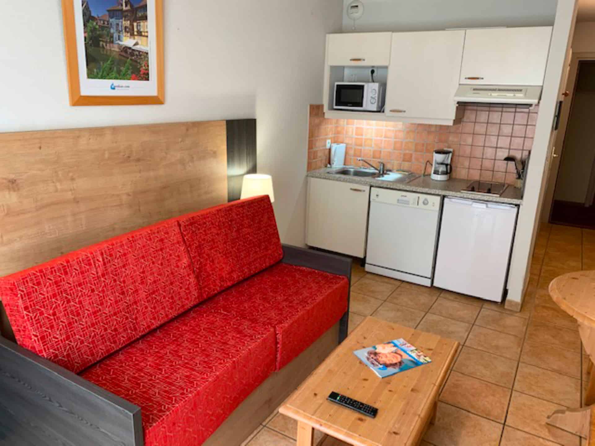 Salon et kitchenette d'un appartement de la résidence de vacances Goélia Le Domaine du Golf à Ammerschwihr / Colmar Salon et kitchenette d'un appartement de la résidence de vacances Goélia Le Domaine du Golf à Ammerschwihr / Colmar