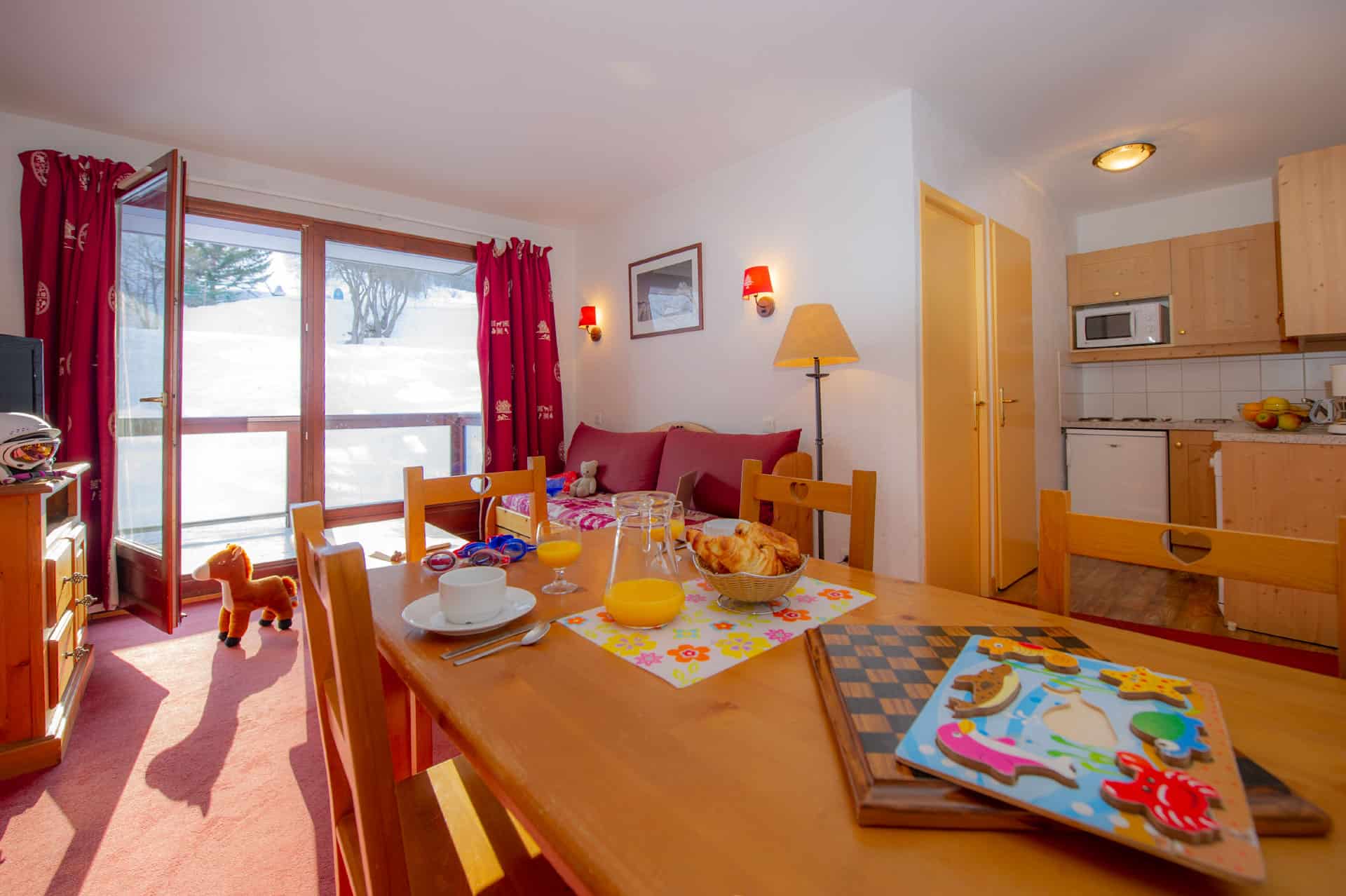 Salon et kitchenette d'un appartement de la résidence de vacances Goélia Les Terrasses du Corbier au Corbier en hiver Salon et kitchenette d'un appartement de la résidence de vacances Goélia Les Terrasses du Corbier au Corbier en hiver