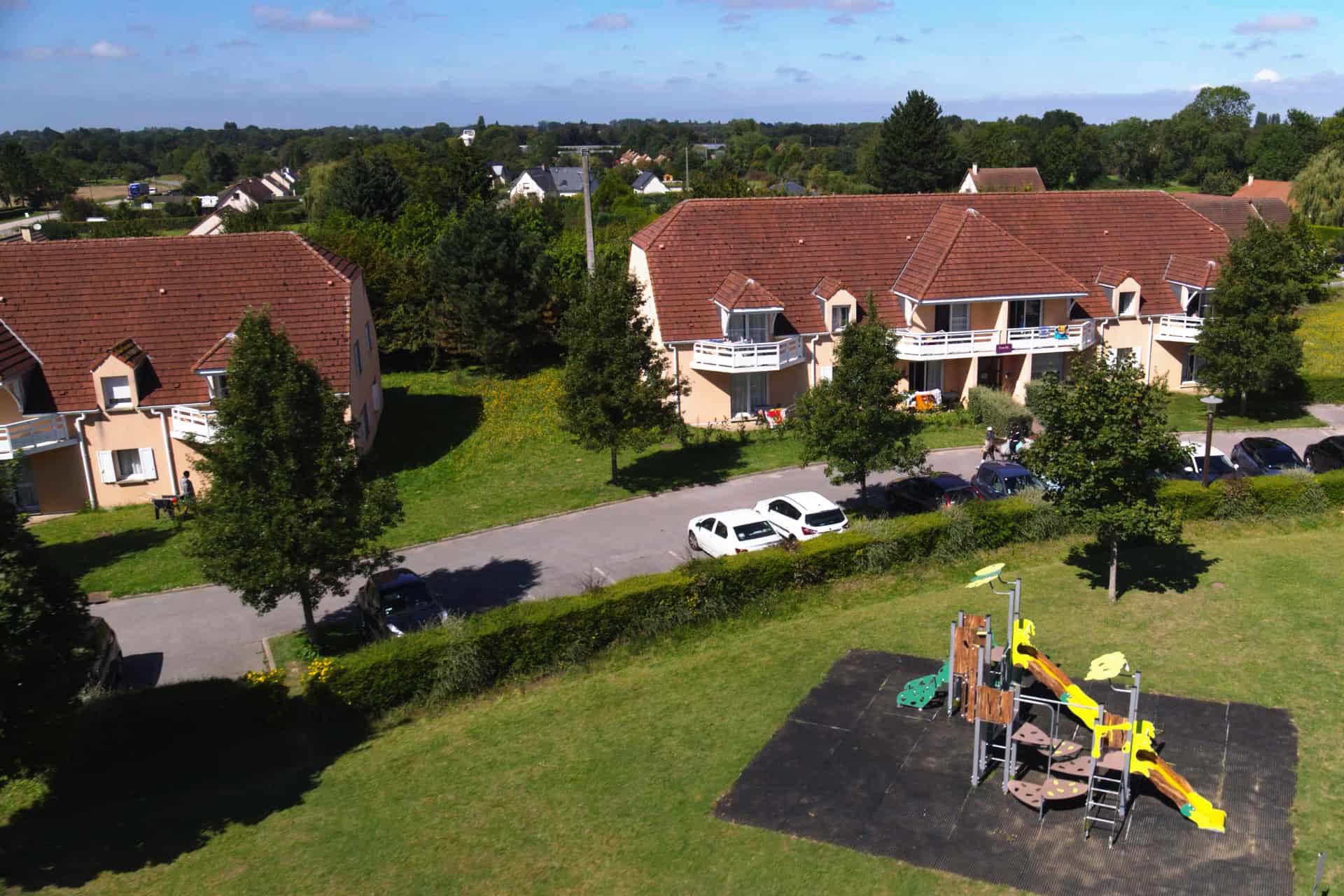Extérieur de la résidence de vacances Goélia Les Portes d'Honfleur à Boulleville et aire de jeux pour enfants Extérieur de la résidence de vacances Goélia Les Portes d'Honfleur à Boulleville et aire de jeux pour enfants
