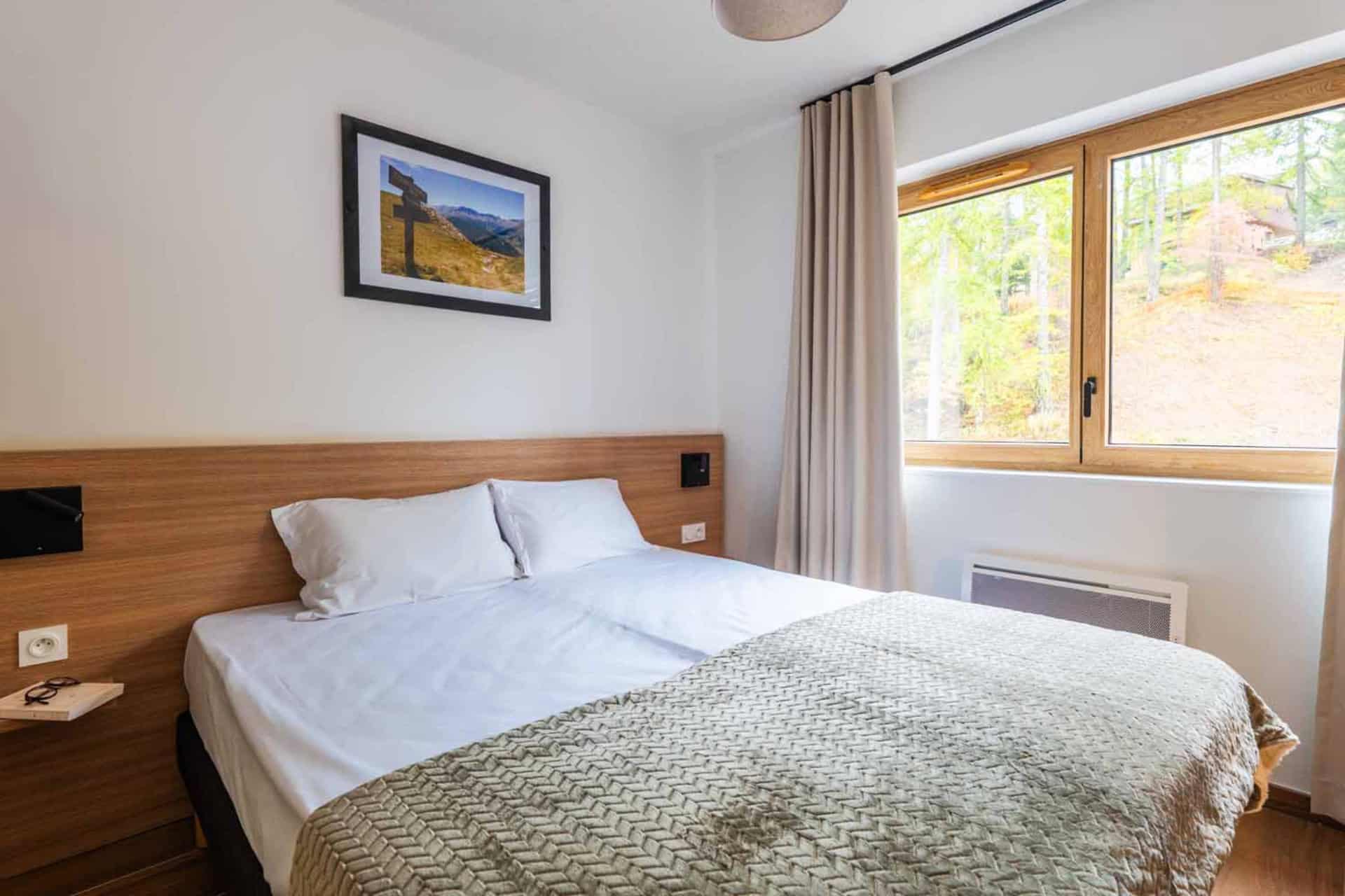 Chambre avec lit double d'un appartement 2 pièces pour 4 personnes de la résidence de vacances Arya Living Stone à Vars dans les Alpes du Sud Chambre avec lit double d'un appartement 2 pièces pour 4 personnes de la résidence de vacances Arya Living Stone à Vars dans les Alpes du Sud
